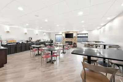 a restaurant with tables and chairs and a kitchen at Comfort Suites Columbus in Columbus