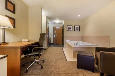 a hotel room with a tub and a desk and chairs at Comfort Inn Warren I-69 in Warren