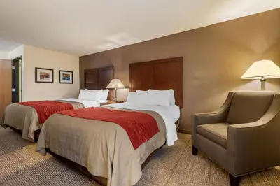 a hotel room with two beds and a chair at Comfort Inn Warren I-69 in Warren