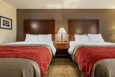 a hotel room with two beds with red sheets at Comfort Inn Warren I-69 in Warren