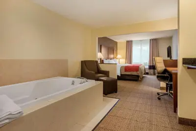 a hotel room with a tub and a bedroom at Comfort Inn Warren I-69 in Warren