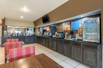 a fast food restaurant with a bar with red chairs at Comfort Inn Warren I-69 in Warren