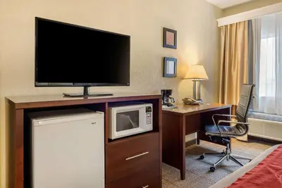 a hotel room with a desk with a microwave and a television at Comfort Inn Warren I-69 in Warren