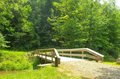 a wooden bridge over a river in a forest at Berlin Resort in Millersburg