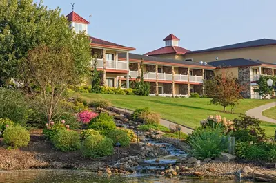 a house with a river in front of a building at Berlin Resort in Millersburg