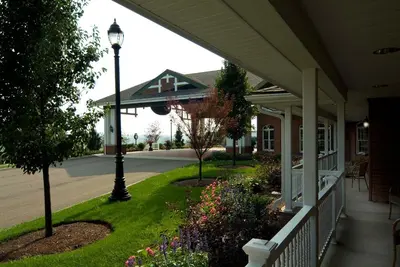 a porch of a house with a lamp post and flowers at Carlisle Inn in Sugarcreek