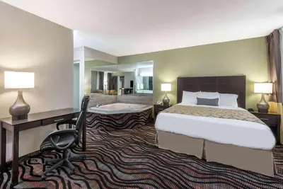 a hotel room with a bed and a desk and a tub at Baymont by Wyndham Cambridge in Cambridge
