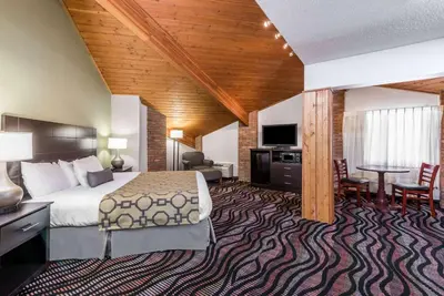 a hotel room with a bed and a table and chairs at Baymont by Wyndham Cambridge in Cambridge