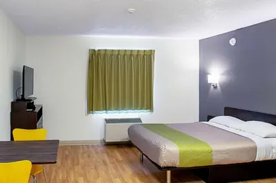 a hotel room with a bed and a table and a chair at Studio Lodge - Cincinnati - Springdale in Springdale