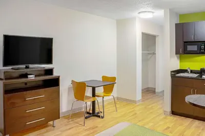 a small room with a table with chairs and a television at Studio Lodge - Cincinnati - Springdale in Springdale