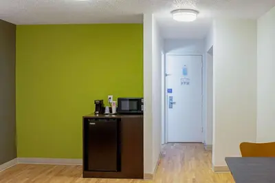 a room with a green wall and a refrigerator at Studio Lodge - Cincinnati - Springdale in Springdale