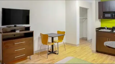 a kitchen with a small table with two chairs and a television at Studio Lodge - Cincinnati - Springdale in Springdale