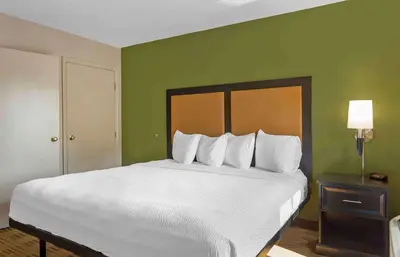 a large white bed in a room with green walls at Extended Stay America Suites - Cincinnati - Blue Ash - Reagan Hwy in Blue Ash