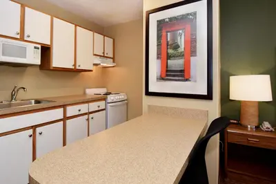 a small kitchen with a sink and a table with a lamp at Suburban Studios Columbus - Dublin in Dublin