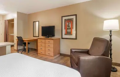 a hotel room with a bed and a desk with a television at Extended Stay America Suites - Dayton - South in Dayton