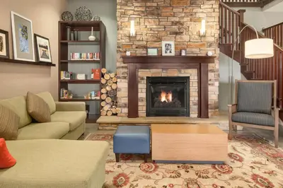 a living room with a fireplace and a couch at Country Inn & Suites by Radisson, Lima in Lima