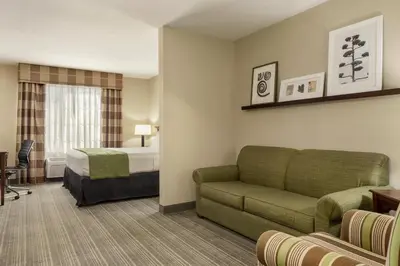 a hotel room with a couch and a bed at Country Inn & Suites by Radisson, Lima in Lima