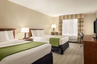 a hotel room with two beds and a television at Country Inn & Suites by Radisson, Lima in Lima