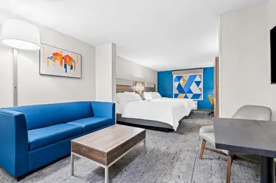 a hotel room with a bed and a blue couch at Holiday Inn Express Washington Court House by IHG in Washington Court House