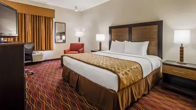 a hotel room with a large bed and a red chair at Best Western B R Guest in Zanesville