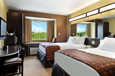 a hotel room with two beds and a desk at Microtel Inn & Suites by Wyndham Marietta in Marietta