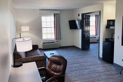 a hotel room with a couch and a chair and a table at Ramada by Wyndham Sparta/At Speedway in Sparta