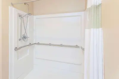 a bathroom with a shower curtain and a white door at Ramada by Wyndham Sparta/At Speedway in Sparta