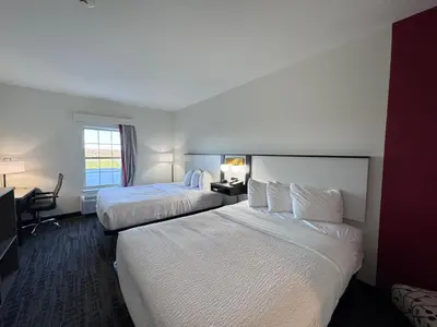 a hotel room with two beds and a desk at Ramada by Wyndham Sparta/At Speedway in Sparta