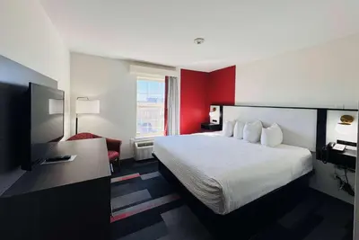 a hotel room with a bed and a red wall at Ramada by Wyndham Sparta/At Speedway in Sparta