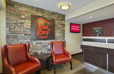 a waiting room with two chairs and a red roop sign at Red Roof Inn Charleston West - Hurricane, WV in Teays Valley Estates