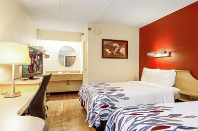 a hotel room with two beds and a table at Red Roof Inn Charleston West - Hurricane, WV in Teays Valley Estates