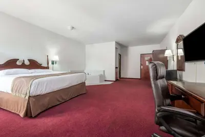 a hotel room with a large bed and a desk at Super 8 by Wyndham Grayson in Grayson