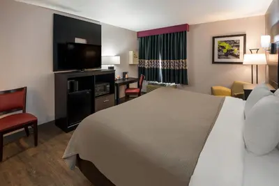 a hotel room with a bed and a desk with a television at Quality Inn & Suites Cincinnati I-275 in Springdale