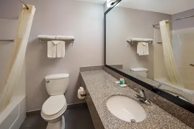 a bathroom with a toilet and a sink and a mirror at Quality Inn & Suites Cincinnati I-275 in Springdale