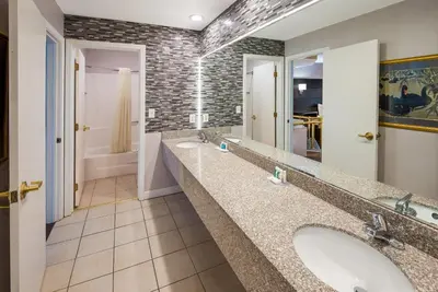 a bathroom with two sinks and two mirrors at Quality Inn & Suites Cincinnati I-275 in Springdale