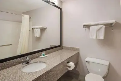 a bathroom with a toilet and a sink and a mirror at Quality Inn & Suites Cincinnati I-275 in Springdale