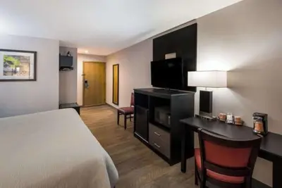 a hotel room with a bed and a desk with a television at Quality Inn & Suites Cincinnati I-275 in Springdale