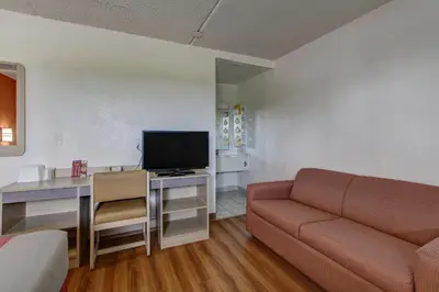 a living room with a couch and a desk with a television at Motel 6-North Ridgeville, OH - Cleveland Intl Airport - N Ridgeville in North Ridgeville