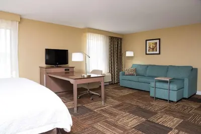 a hotel room with a bed and a couch and a tv at Hampton Inn & Suites Fremont in Fremont