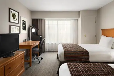 a hotel room with two beds and a desk and a television at Country Inn & Suites by Radisson, Columbus Airport, OH in Columbus