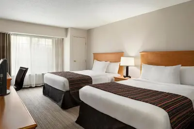 a hotel room with two beds and a window at Country Inn & Suites by Radisson, Columbus Airport, OH in Columbus