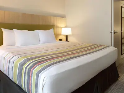 a hotel room with a large bed with a colorful striped blanket at Country Inn & Suites by Radisson, Columbus Airport, OH in Columbus