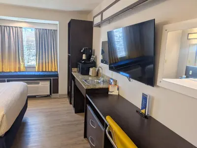 a hotel room with a bed and a large television at Microtel Inn & Suites by Wyndham Wheeling at The Highlands in Triadelphia