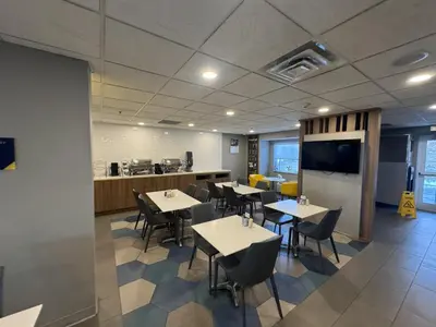 a dining room with tables and chairs and a kitchen at Microtel Inn & Suites by Wyndham Wheeling at The Highlands in Triadelphia