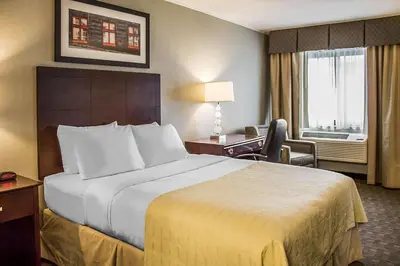 a hotel room with a large bed and a desk at Quality Inn Cambridge in Cambridge