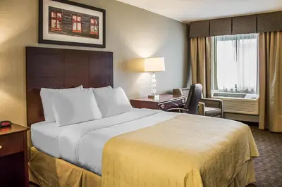 a hotel room with a large bed and a desk at Quality Inn Cambridge in Cambridge