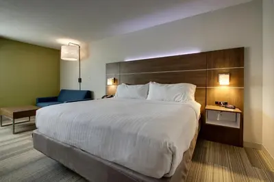 a hotel room with a large bed and a blue chair at Holiday Inn Express & Suites Wapakoneta by IHG in Wapakoneta