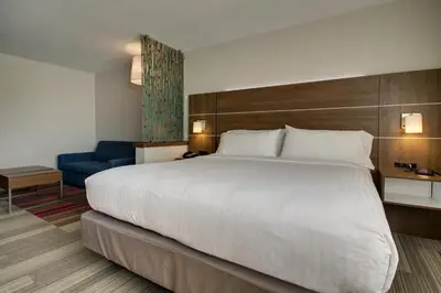 a hotel room with a large bed and a blue chair at Holiday Inn Express & Suites Wapakoneta by IHG in Wapakoneta