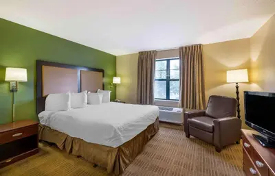 a hotel room with a large bed and a chair at Extended Stay America Suites - Akron - Copley - East in Copley