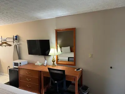 a hotel room with a desk with a bed and a mirror at South Shore Inn in Sandusky